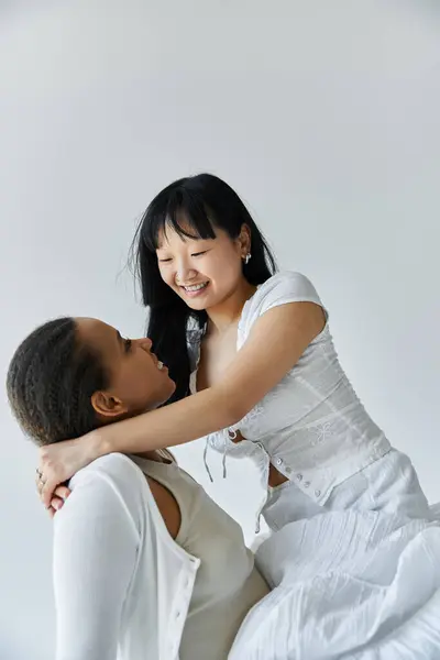 A young interracial lesbian couple share a tender moment, embracing in a studio setting. — Stock Photo