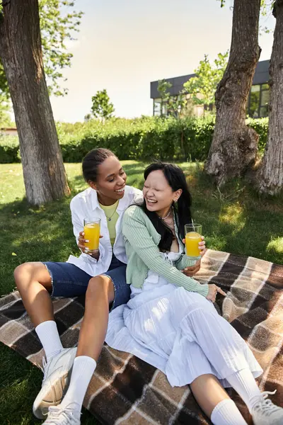 A young lesbian couple enjoys a picnic on a sunny day, laughing together. — Stock Photo