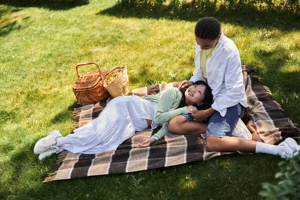 A young lesbian couple enjoys a picnic in the park, sharing a moment of intimacy and laughter. — Stock Photo