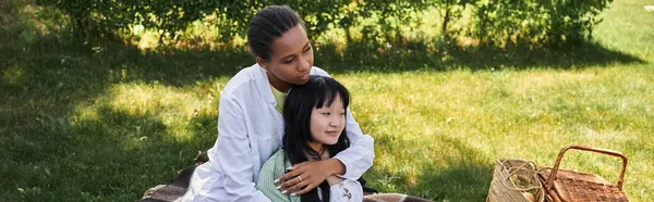 A lesbian couple embraces during a picnic in a grassy park. — Stock Photo