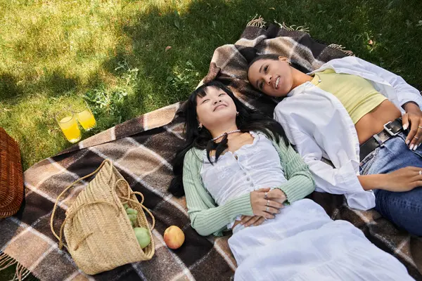 Ein junges lesbisches Paar entspannt sich auf einer Picknickdecke, genießt die Sonne und Gesellschaft füreinander. — Stockfoto