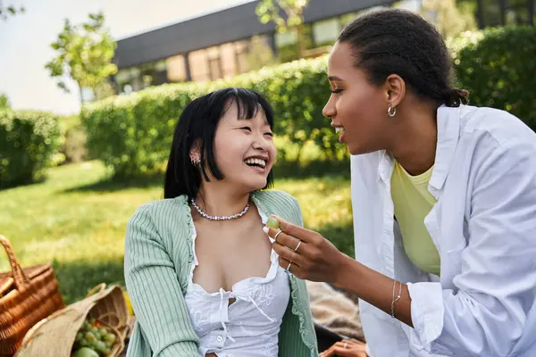 Two young women enjoy a picnic outdoors, sharing a laugh and a moment of intimacy. — Stock Photo