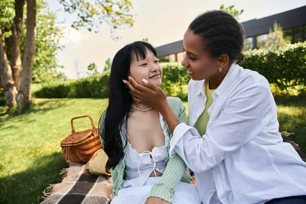 Due giovani donne condividono un momento tenero mentre fanno un picnic in una giornata di sole. — Foto stock