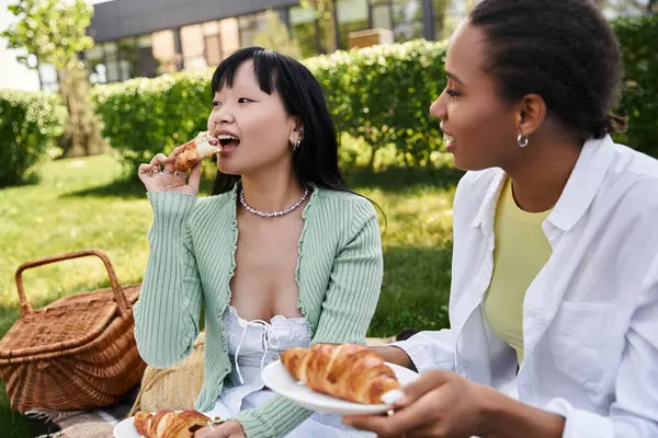 Two women share a meal of pastries and laughter during an outdoor picnic. — Stock Photo