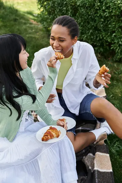 Ein lesbisches Paar genießt ein Picknick im Park, lacht und teilt einen Snack. — Stockfoto