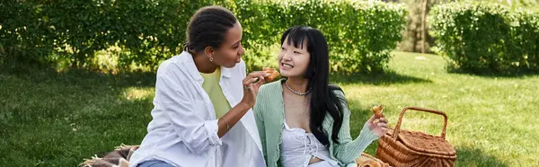 Due giovani donne condividono un pranzo al sacco all'aperto, circondate da un verde lussureggiante. — Foto stock
