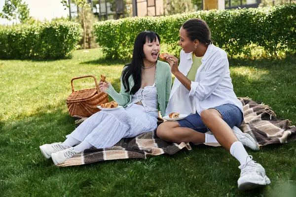 Due giovani donne condividono un momento spensierato durante un picnic, godendo di un pomeriggio rilassante in un parco soleggiato. — Foto stock