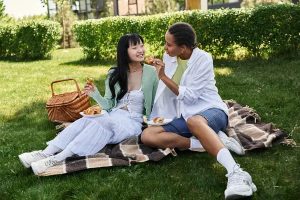 Una coppia lesbica si gode un pranzo al sacco nel parco, condividendo una risata e un boccone da mangiare. — Foto stock