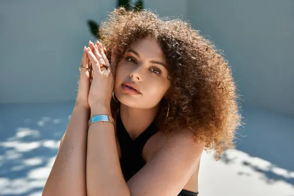 A woman with beautiful curly hair in a black swimsuit poses by a pool, radiating summer confidence. — Stock Photo