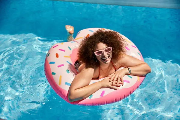 A woman in a bikini floats on a donut-shaped pool float, smiling and enjoying the summer sun. — Stock Photo