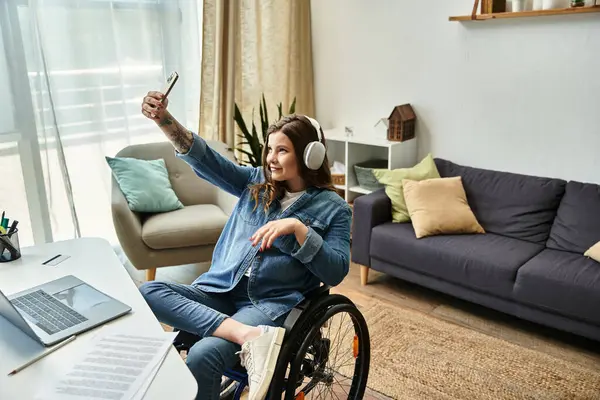 A young woman in a wheelchair takes a selfie in a modern apartment, showcasing a comfortable and accessible lifestyle. — Stock Photo