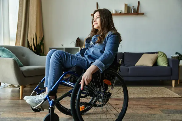 Eine junge Frau im Rollstuhl sitzt nachdenklich in ihrer modernen Wohnung. — Stockfoto