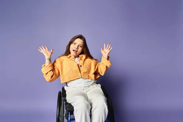 Young woman in a wheelchair poses in trendy casual attire in a studio. Vibrant purple backdrop contrasts with her yellow jacket — Stock Photo