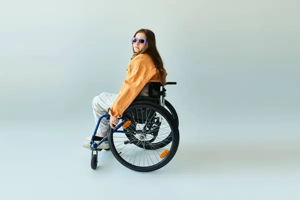 A young woman in a wheelchair sits stylishly in a studio setting. — Stock Photo