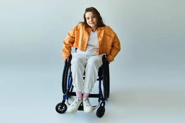 A confident young woman in a wheelchair with long brown hair smiles at the camera in a stylish orange jacket — Stock Photo