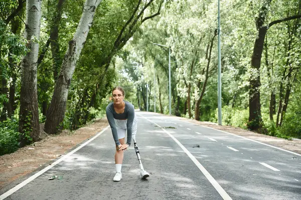 A determined young woman exercises outdoors, showcasing strength with a prosthetic leg in a serene landscape. — Stock Photo