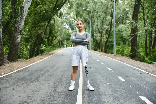 A determined young woman enjoys outdoor fitness, confidently showcasing her prosthetic leg amid lush greenery. — Stock Photo