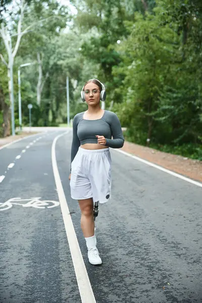 Una giovane donna si allena tranquillamente all'aperto, usando la sua gamba protesica mentre ascolta musica. — Foto stock