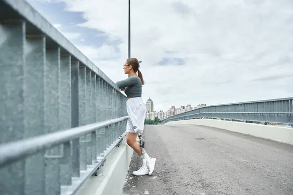 Una giovane donna determinata in abbigliamento sportivo si impegna in attività di fitness su un ponte panoramico. — Foto stock