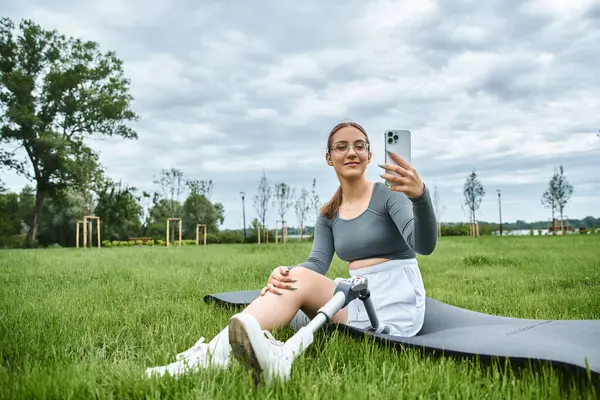 A young woman relaxes on a mat, capturing the moment outdoors with her prosthetic leg visible. — Stock Photo
