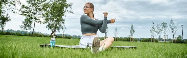 Uma jovem se estende ao ar livre, mostrando determinação enquanto desfruta de seu treino ao sol. — Fotografia de Stock