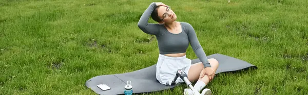 A young woman with a prosthetic leg stretches while working out outdoors in comfortable sportswear. — Stock Photo