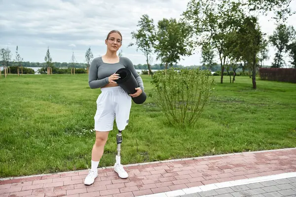 A young woman confidently works out outdoors, showcasing her prosthetic leg while dressed in vibrant sportswear. — Stock Photo