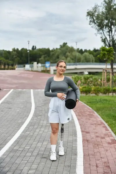 Una giovane donna vivace abbraccia il fitness all'aperto, esercitandosi con fiducia con la sua gamba protesica. — Foto stock