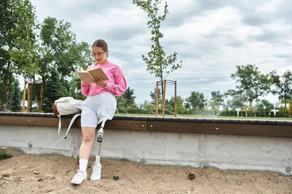 A young woman in sportswear sits outdoors, engaging with a book while showing her resilient spirit. — Stock Photo