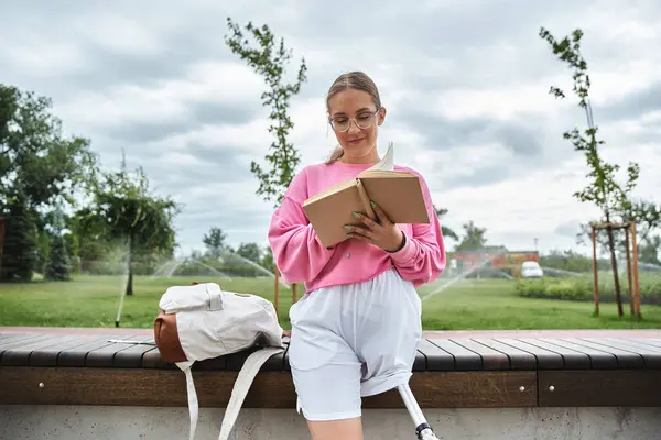 A young woman enjoys her day outdoors, experiencing relaxation while reading in the park. — Stock Photo