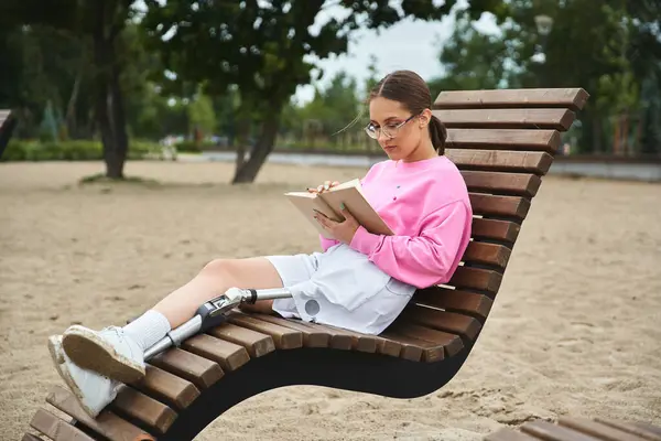 A determined young woman enjoys reading outdoors, sitting on bench — Stock Photo