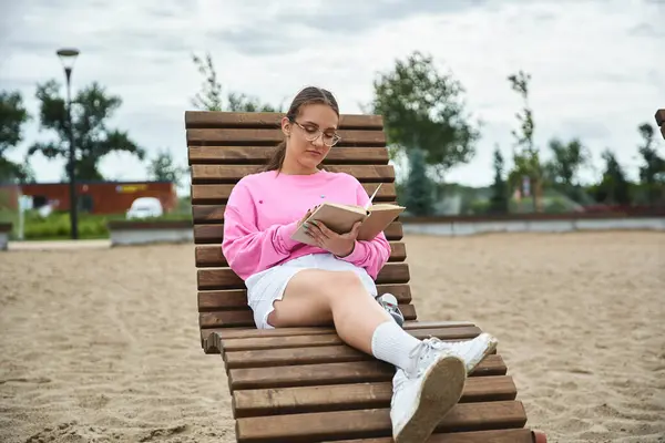 A young woman engages in reading outdoors, showcasing her prosthetic leg — Stock Photo