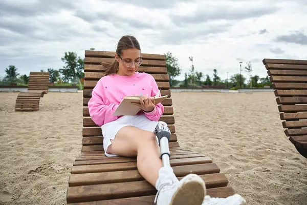 A young woman relaxes on a beach chair, reading a book while enjoying the outdoors moments — Stock Photo