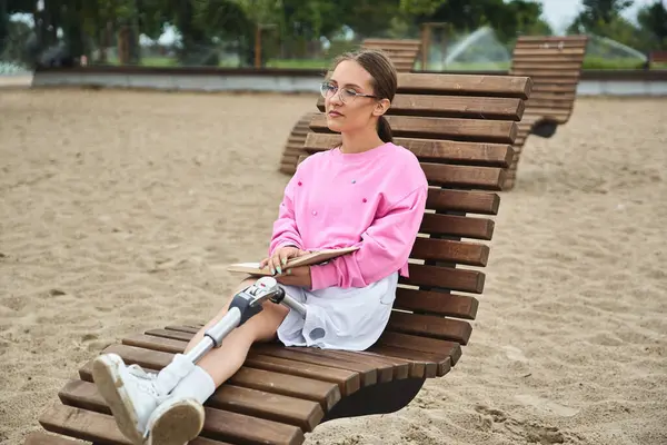 A young woman relaxes outdoors, embracing life with a prosthetic leg while enjoying her surroundings. — Stock Photo