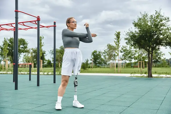A determined young woman stretches her arms outdoors while embracing an active lifestyle. — Stock Photo