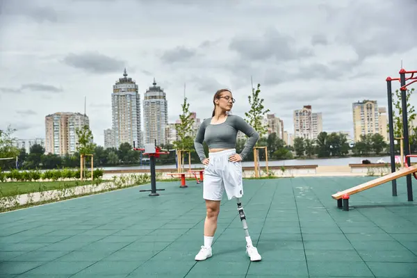 Determinata giovane donna esercita con fiducia all'aperto, abbracciando il fitness e la natura con la sua gamba protesica. — Foto stock