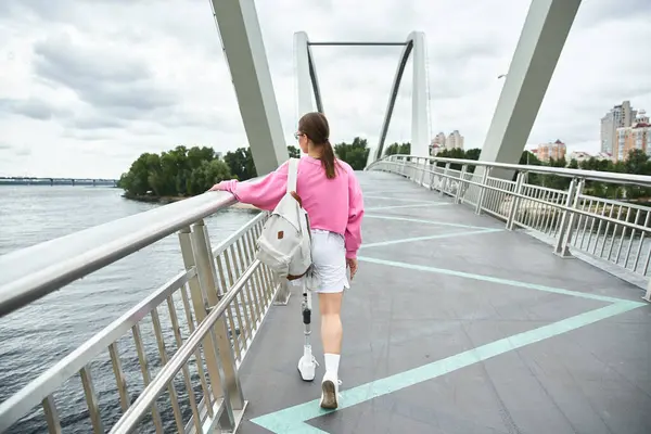 Una giovane donna determinata con una gamba protesica che cammina su un pittoresco ponte. — Foto stock
