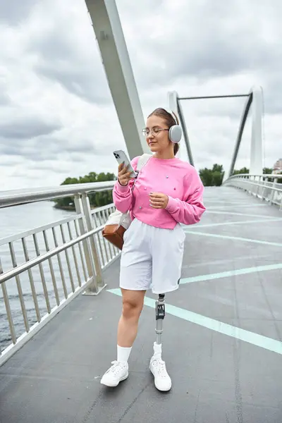 A young woman with a prosthetic leg walking outdoors, embracing music and fresh air — Stock Photo