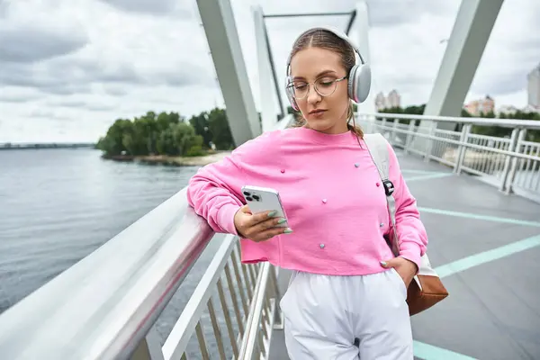 Uma jovem se envolve em seu smartphone, ouvindo podcast em fones de ouvido — Fotografia de Stock