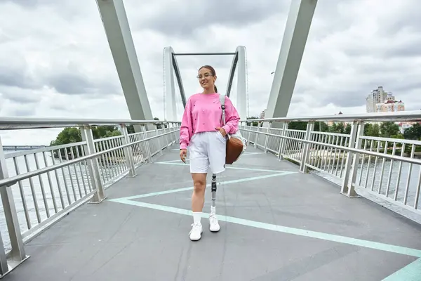 Una giovane donna in abbigliamento sportivo cammina tranquillamente all'aperto su un ponte, abbracciando il suo stile di vita attivo. — Foto stock
