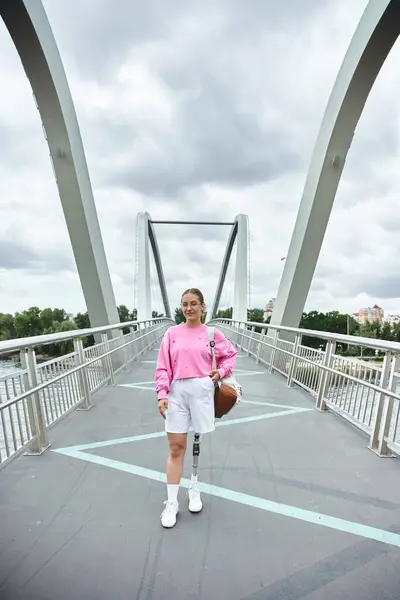 Una giovane donna con una gamba protesica che cammina all'aperto su un ponte, abbracciando fitness e natura. — Foto stock