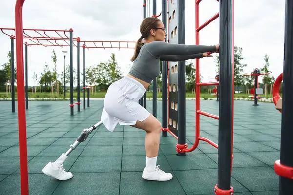 A determined young woman workout outdoors, using a prosthetic leg while enjoying the exercise. — Stock Photo