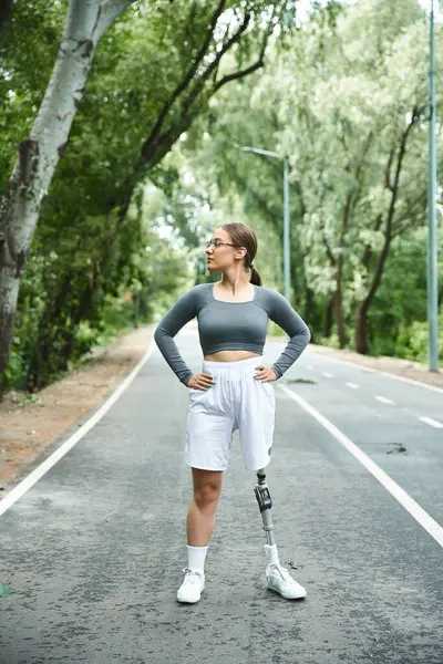 A determined young woman with a prosthetic leg confidently embraces her workout outdoors. — Stock Photo
