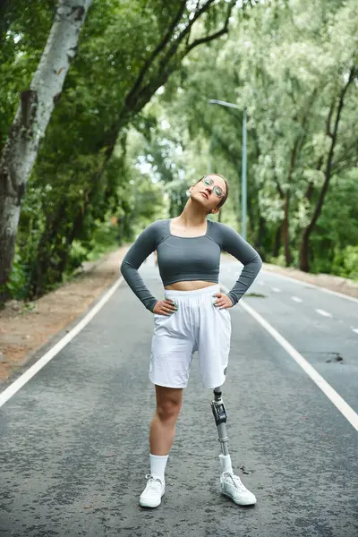 A young woman in sportswear confidently poses outdoors, showcasing her strength and determination. — Stock Photo