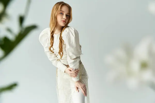 A beautiful young woman poses gracefully with delicate flowers nearby. — Stock Photo