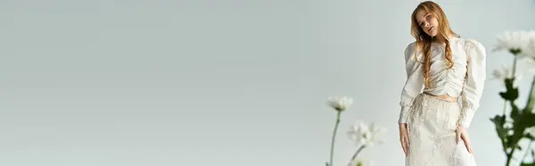 A beautiful young woman poses gracefully among blooming flowers. — Stock Photo