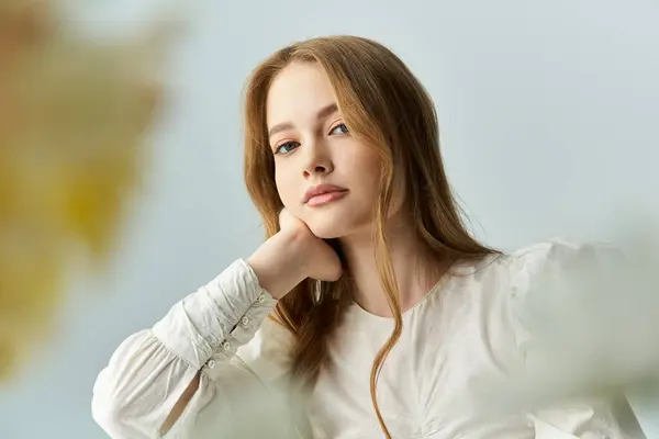 A young woman gently leans on her hand, adorned with flowers in a tranquil space. — Stock Photo
