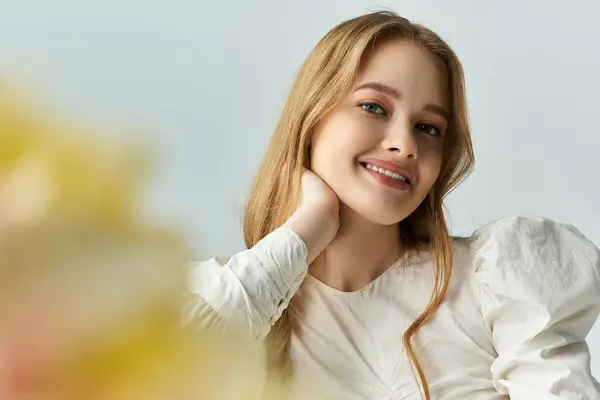 A joyful young woman smiles gently near flowers. — Stock Photo