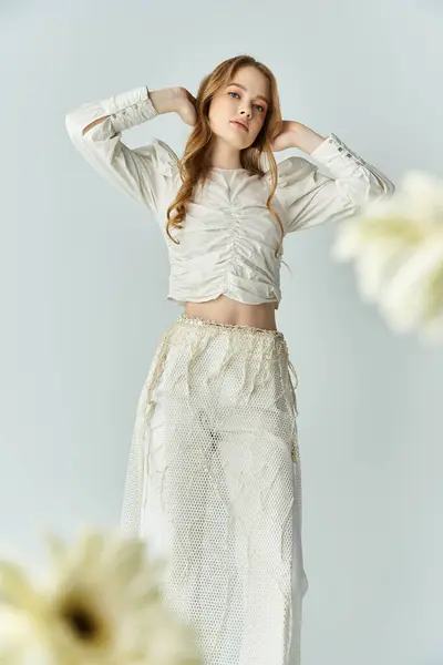 A beautiful young woman wearing elegant attire interacts with delicate flowers. — Stock Photo