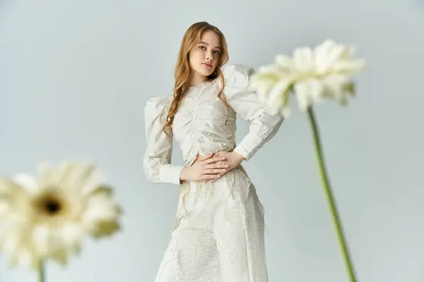 A graceful young woman stands amidst delicate blooms, radiating beauty and calm. — Stock Photo